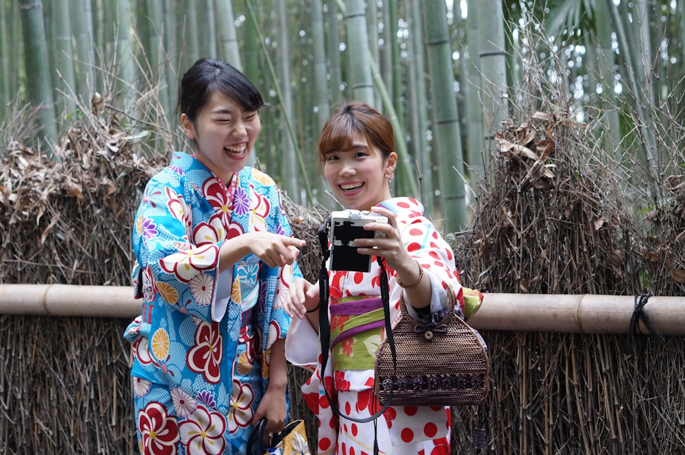 2 girls in blue and red floral kimono standing on brown dried grass during daytime