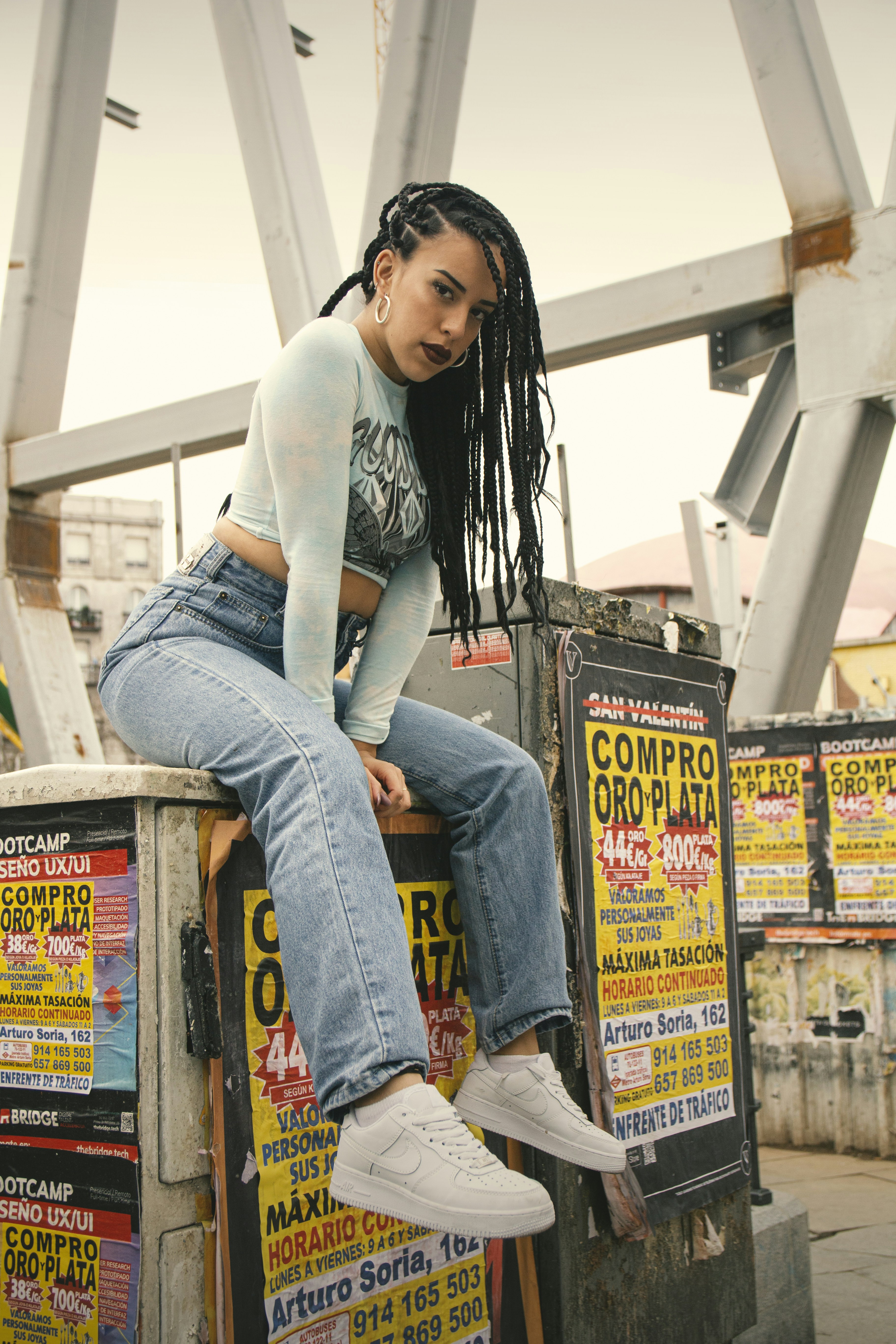 회색 긴 소매 셔츠와 파란색 데님 청바지를 입은 여자 검은 강철 프레임에 서 있다 사진 – Unsplash의 무료 사람의 이미지