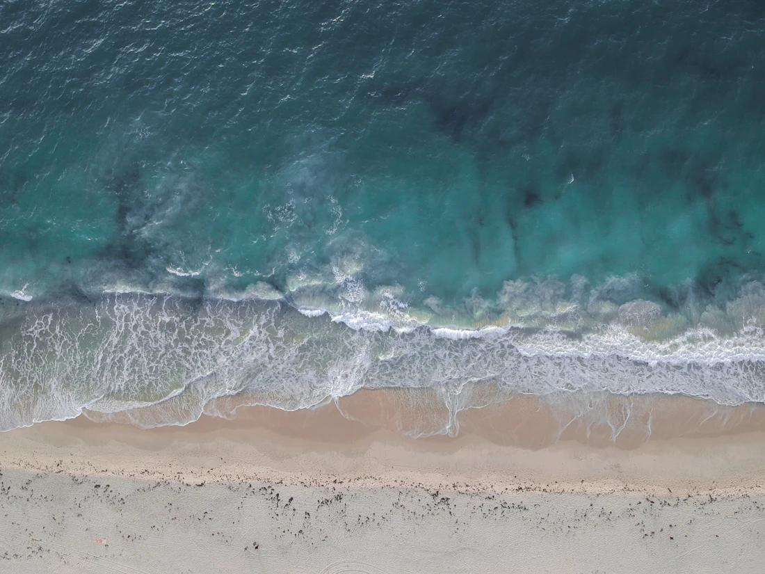 Aerial view of white surf lines meeting a dark shoreline