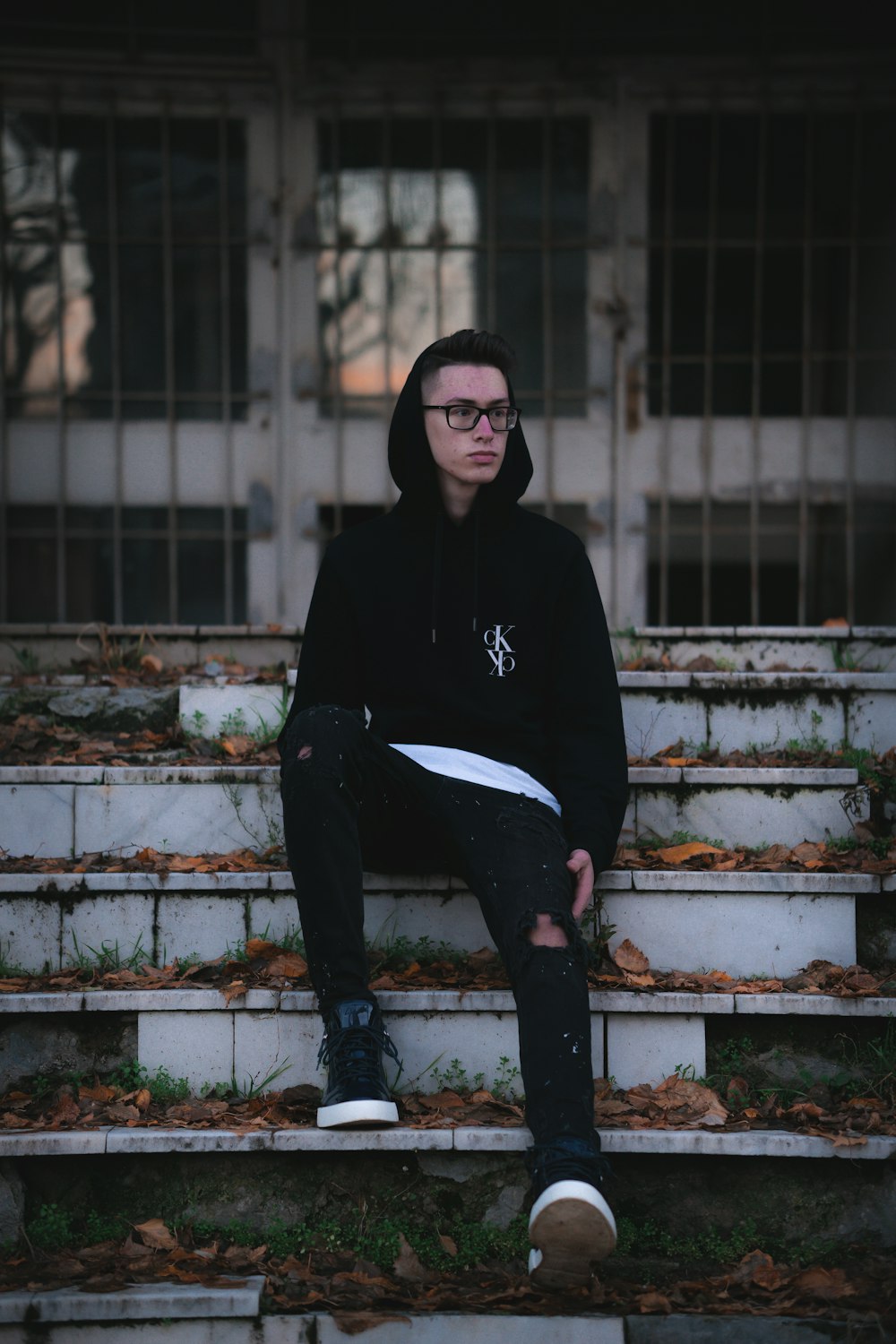 man in black hoodie and black pants sitting on concrete stairs