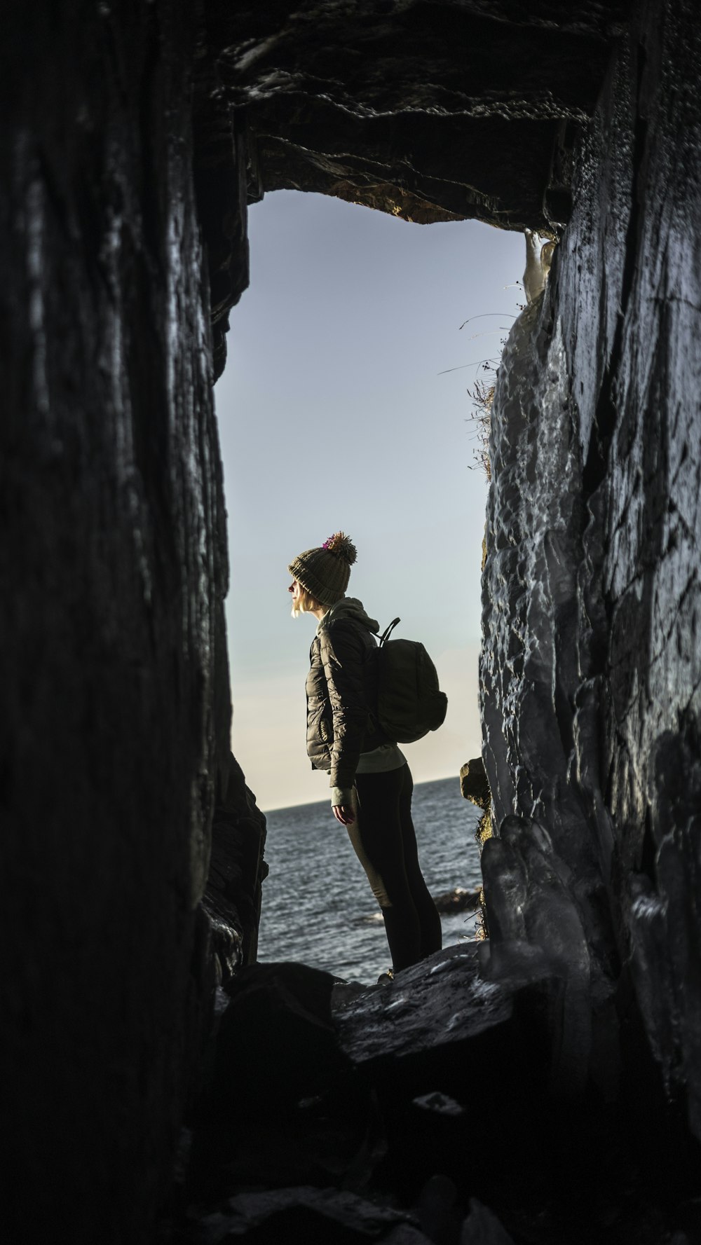homem em jaqueta marrom em pé na formação rochosa durante o dia