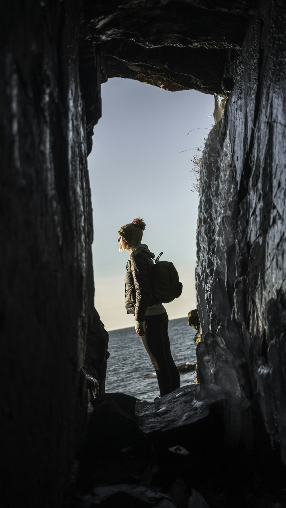 man in brown jacket standing on rock formation during daytime