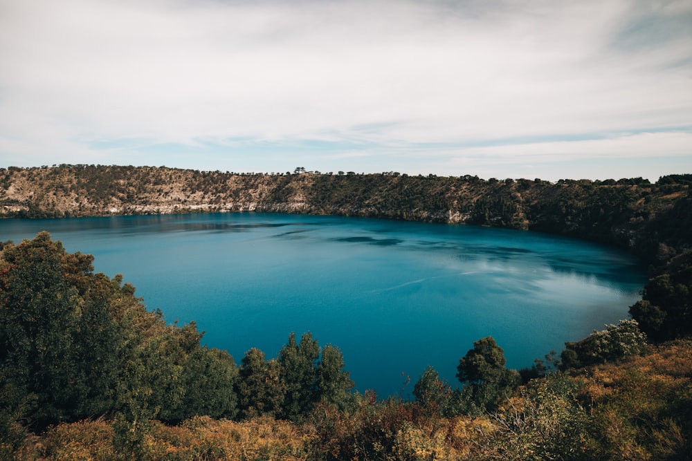 昼間は青空の下、木々に囲まれた青い湖
