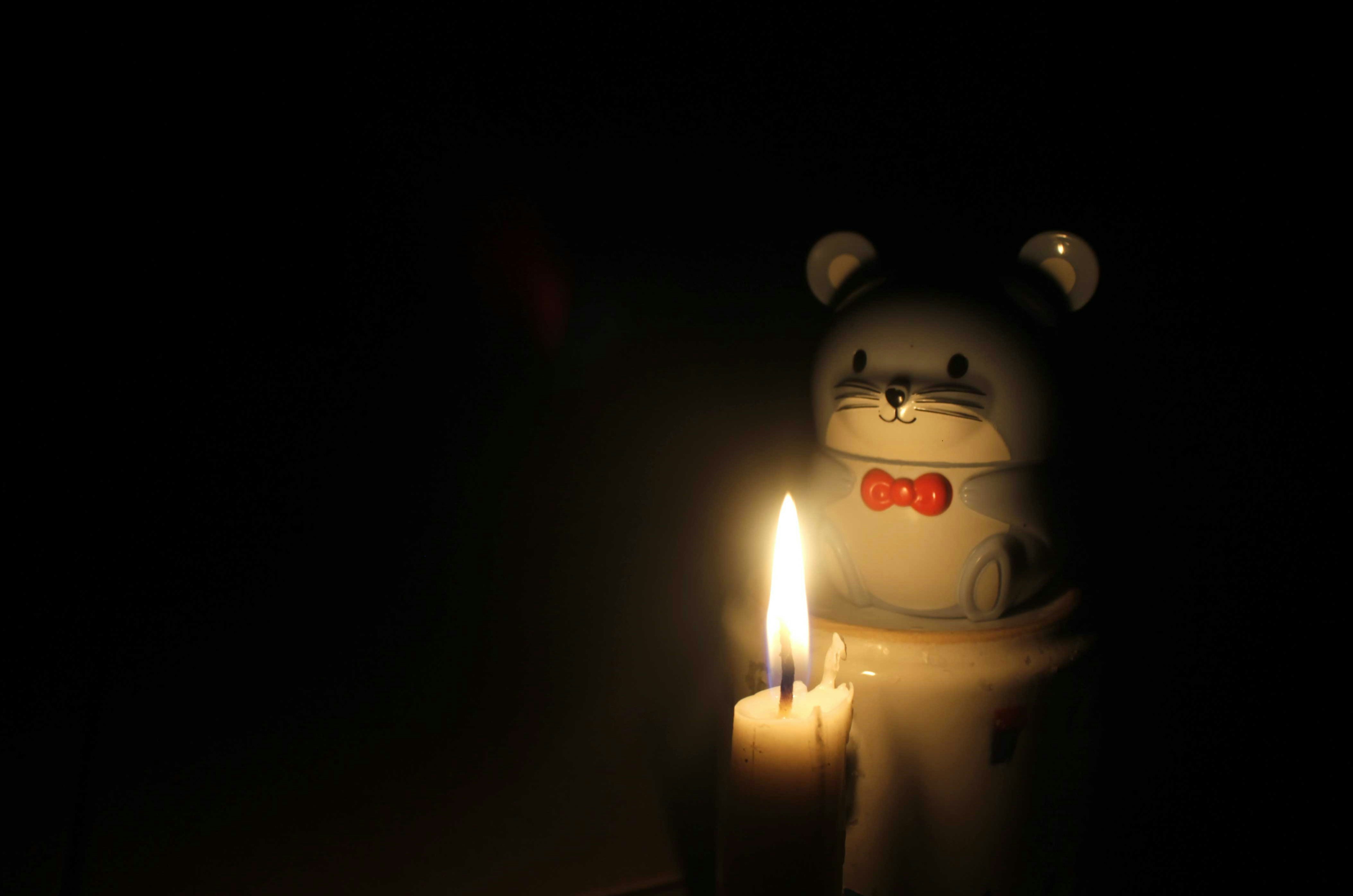 lighted white bear candle on top of brown wooden table
