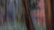 Blurred vertical motion effect in a forest scene with hints of tree trunks. The background includes a mix of green and brown hues, suggesting foliage and bark, while the overall image appears abstract due to the camera movement.
