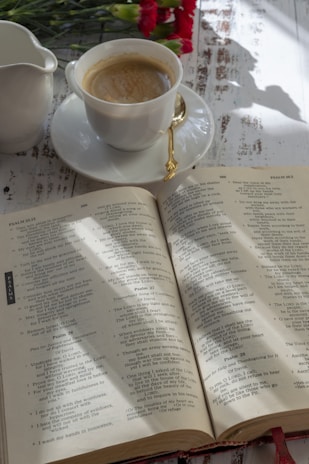 Close-up of the book '1001 questions to ask before you get married' resting on a wooden table with a cup of coffee nearby.