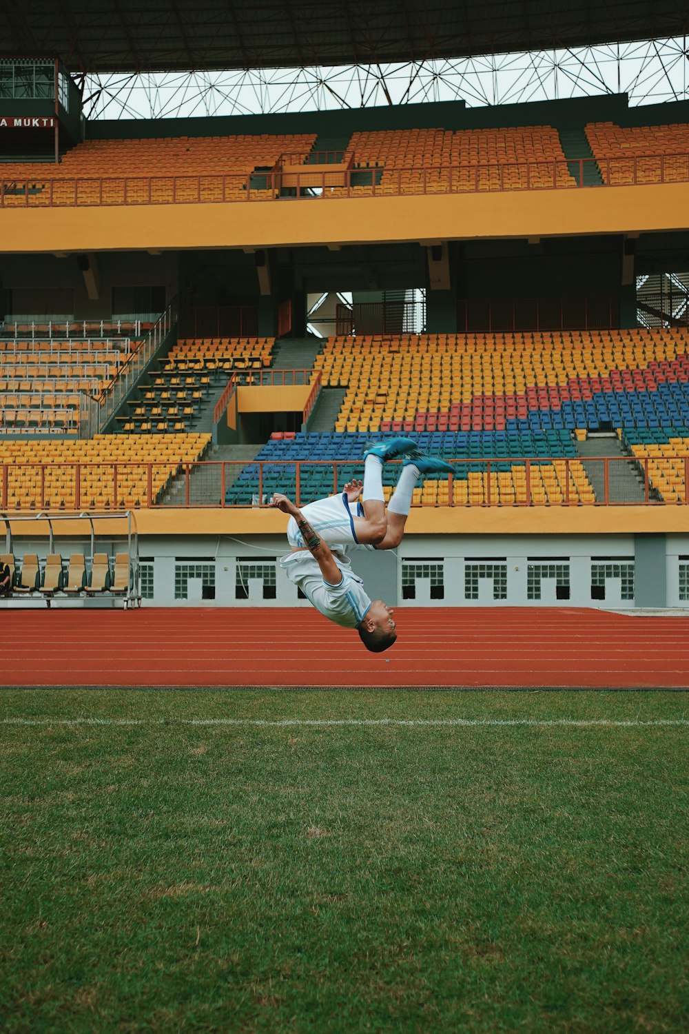 man in white shirt and black shorts jumping on green grass field during daytime