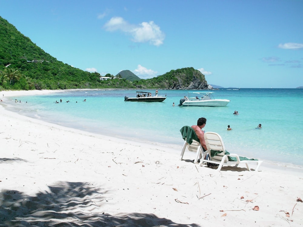 Mujer en bikini verde sentada en tumbona blanca en la playa durante el día