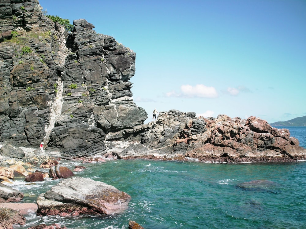 gray rocky mountain beside body of water during daytime