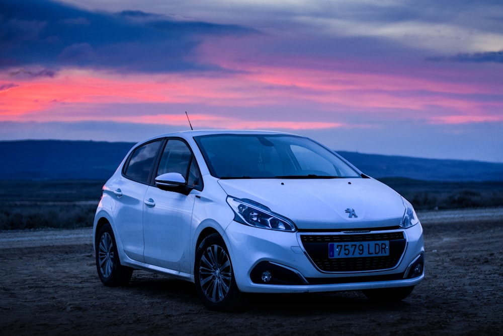 Sedán Honda plateado sobre arena marrón durante la puesta de sol