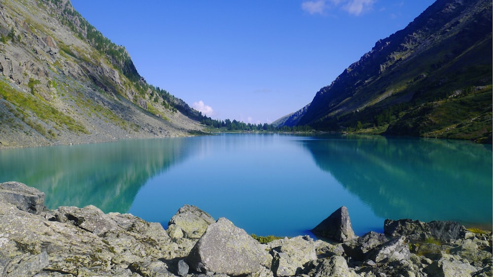 gray rocks beside lake under blue sky during daytime