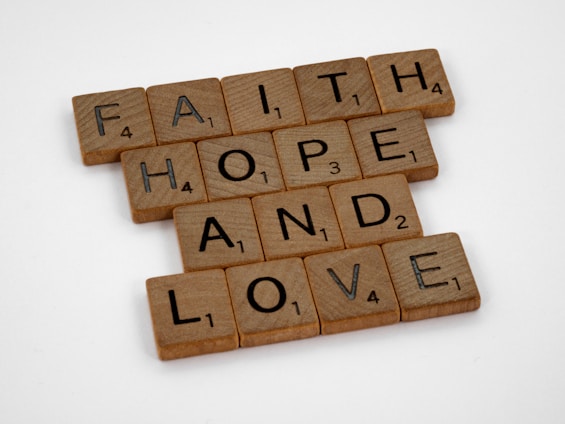 Scrabble tiles arranged to form the words 'FAITH', 'HOPE', and 'LOVE' on a plain white background.