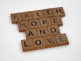 Scrabble tiles arranged to form the words 'FAITH', 'HOPE', and 'LOVE' on a plain white background.