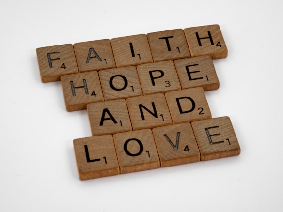 Scrabble tiles arranged to form the words 'FAITH', 'HOPE', and 'LOVE' on a plain white background.