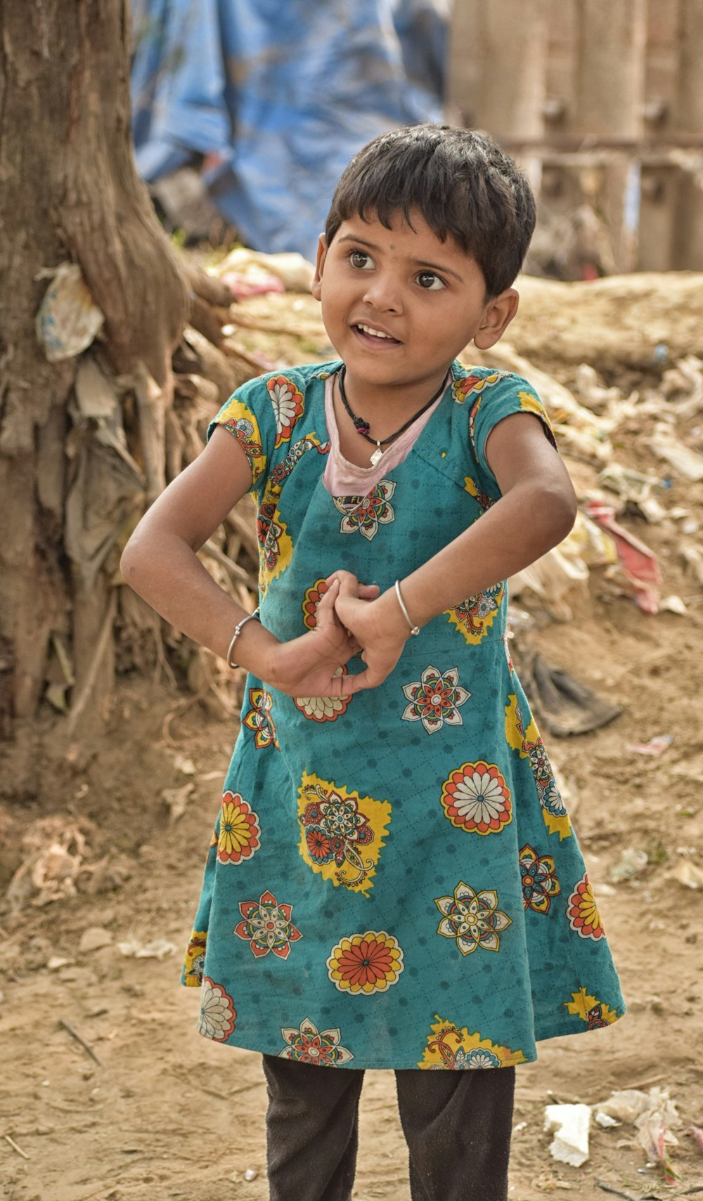 girl in blue and yellow floral dress standing on brown sand during daytime