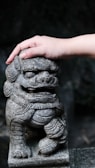 Close-up of hands gently holding a red lion figurine symbolizing strength and care.