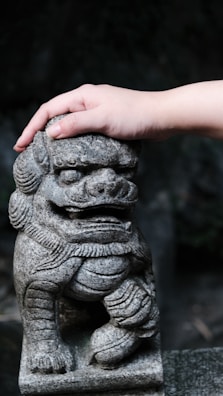 Close-up of hands gently holding a red lion figurine symbolizing strength and care.