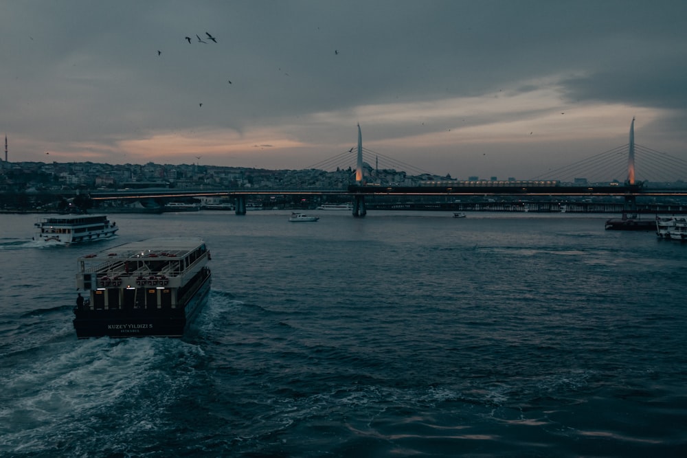 ship on sea near bridge under cloudy sky during daytime