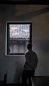 A quiet moment of reflection by a window in a UK accommodation, capturing the spirit of perseverance.