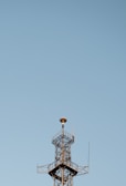 A tall communication tower standing against a clear blue sky during daytime.