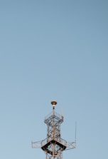Antenna tower standing tall against a clear blue sky in a rural area.