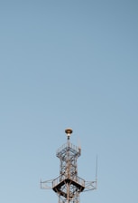 A team of engineers inspecting a newly constructed communication tower against a clear blue sky.