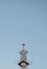 A team of engineers inspecting a newly constructed communication tower against a clear blue sky.