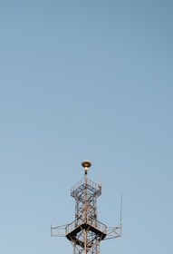 Antenna tower standing tall against a clear blue sky in a rural area.