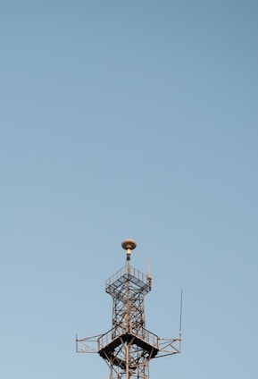 A team of engineers inspecting a newly constructed communication tower against a clear blue sky.
