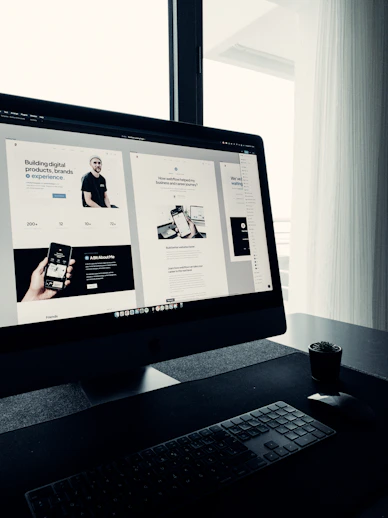 A clean, minimal workspace featuring a laptop displaying a vibrant website design with purple and teal accents.