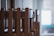 Wooden chairs are stacked in an orderly manner inside a room. Natural light filters through a window in the background, creating a calm and serene atmosphere.