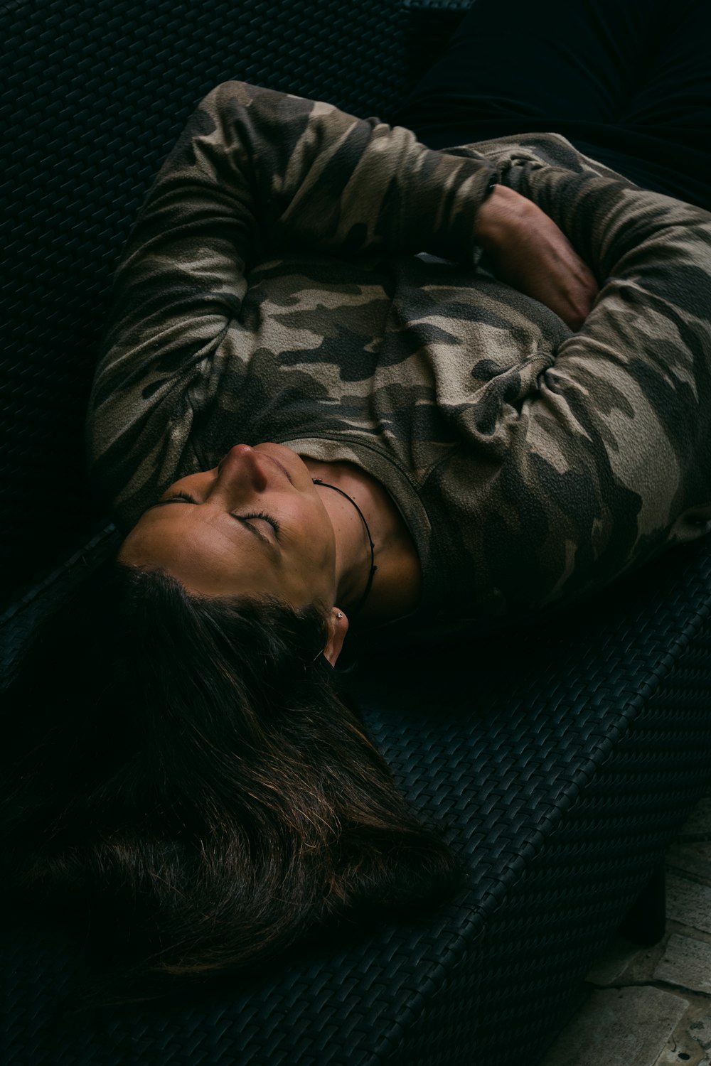 woman in gray and black camouflage jacket lying on black couch