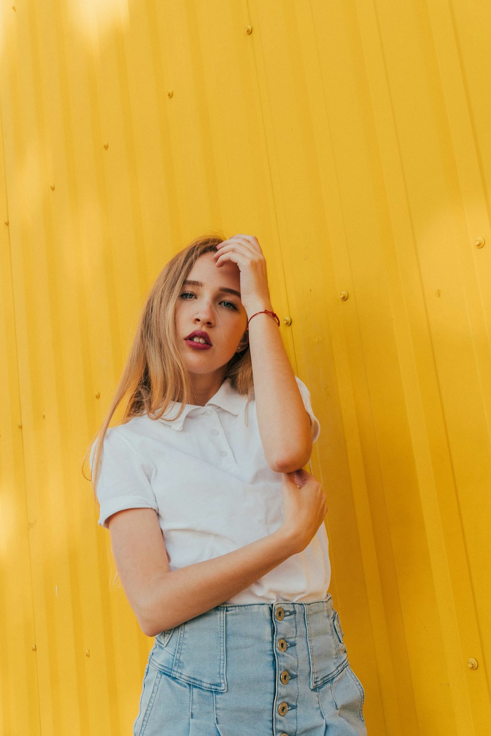 woman in white shirt leaning on yellow wall