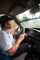 man in white polo shirt driving car during daytime