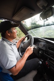 man in white polo shirt driving car during daytime