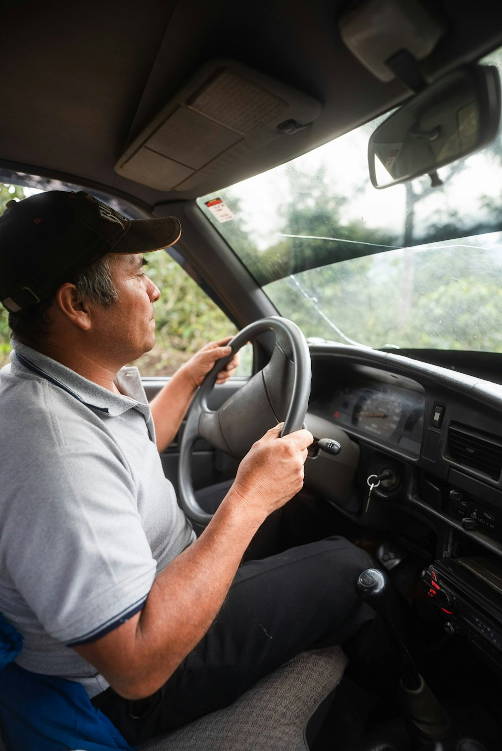 man in white polo shirt driving car during daytime