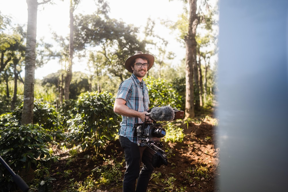 man in blue and white plaid button up t-shirt and black pants holding black dslr