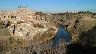 A panoramic view of La Roche-Guyon village nestled along the Seine with its medieval castle perched on chalk cliffs.
