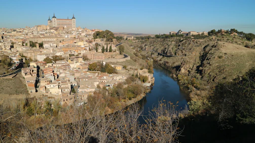 A panoramic view of La Roche-Guyon village nestled along the Seine with its medieval castle perched on chalk cliffs.