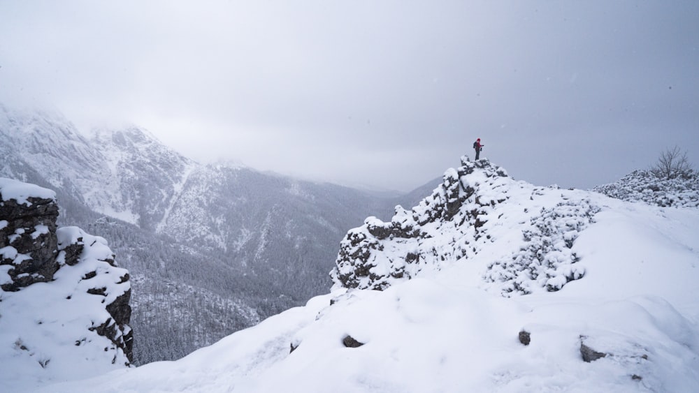 person in red jacket standing on snow covered mountain during daytime