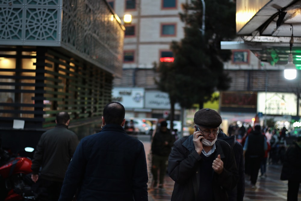 man in black jacket standing near people walking on street during daytime