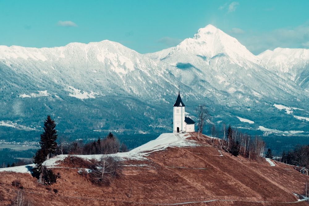 Edificio in calcestruzzo bianco e marrone sul campo di erba marrone vicino alla montagna coperta di neve durante il giorno