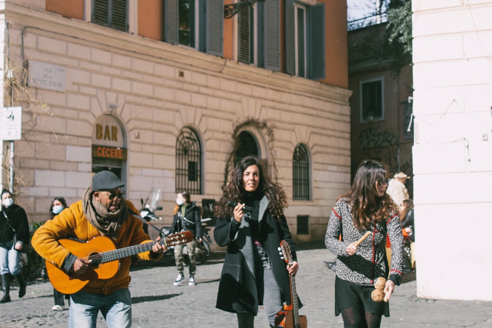 Mujer con abrigo negro sosteniendo guitarra acústica marrón