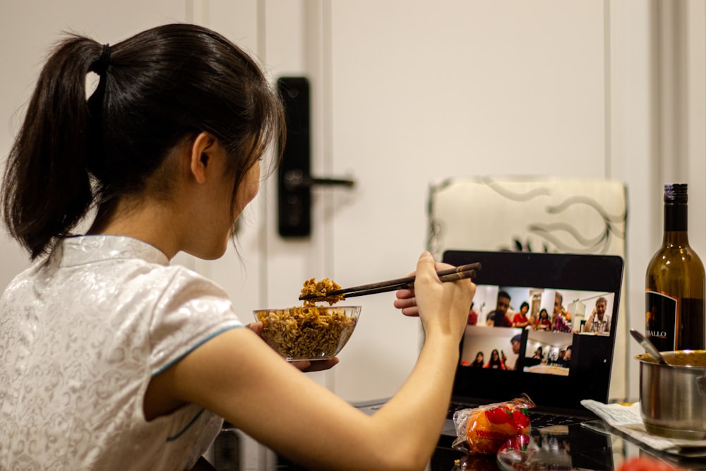 woman in white shirt holding black chopsticks