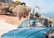 A couple enjoying a scenic drive on a sunny day with their rental car.