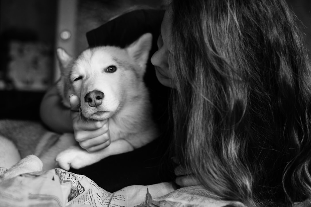 grayscale photo of woman kissing white dog
