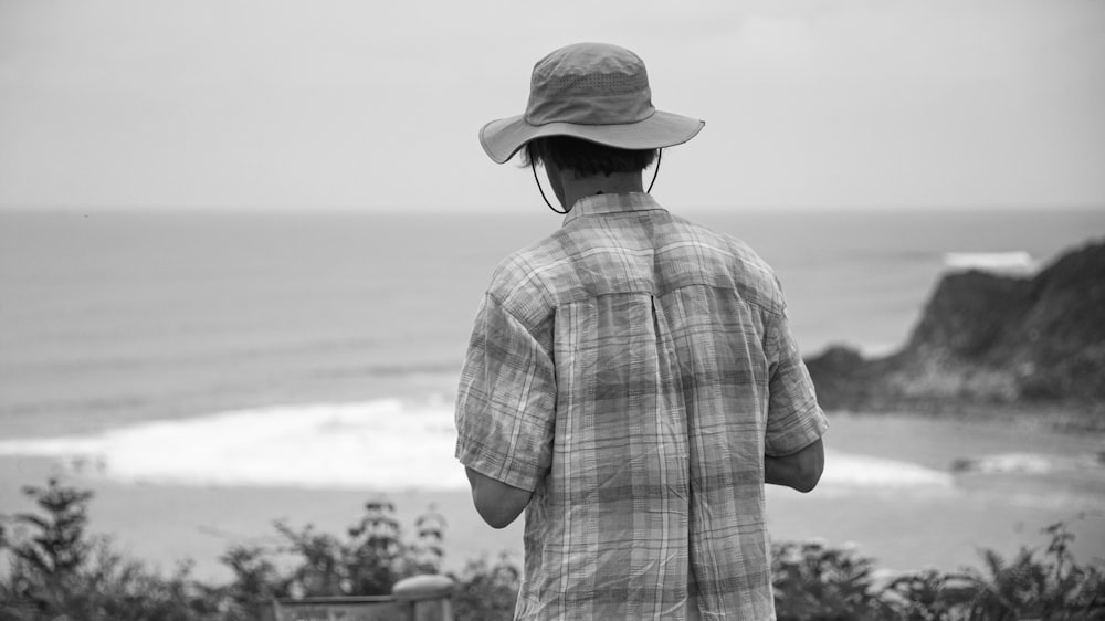 grayscale photo of man wearing hat and plaid shirt