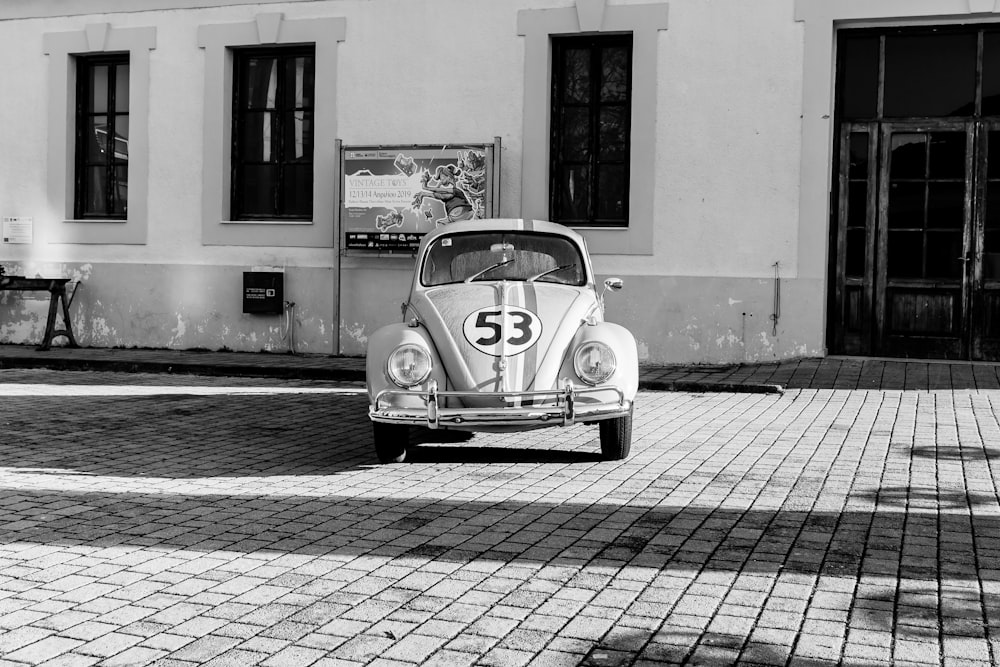 grayscale photo of volkswagen beetle parked on sidewalk