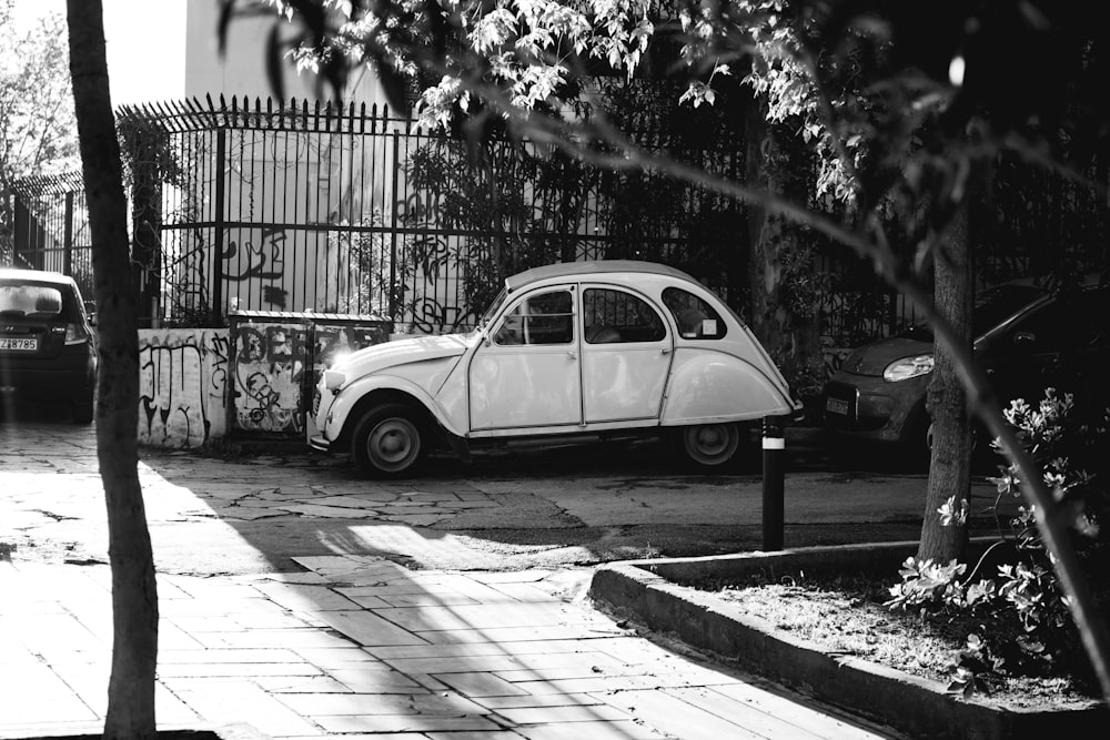 grayscale photo of volkswagen beetle parked on sidewalk