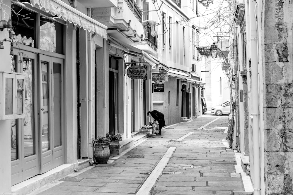 grayscale photo of man sitting on bench near building